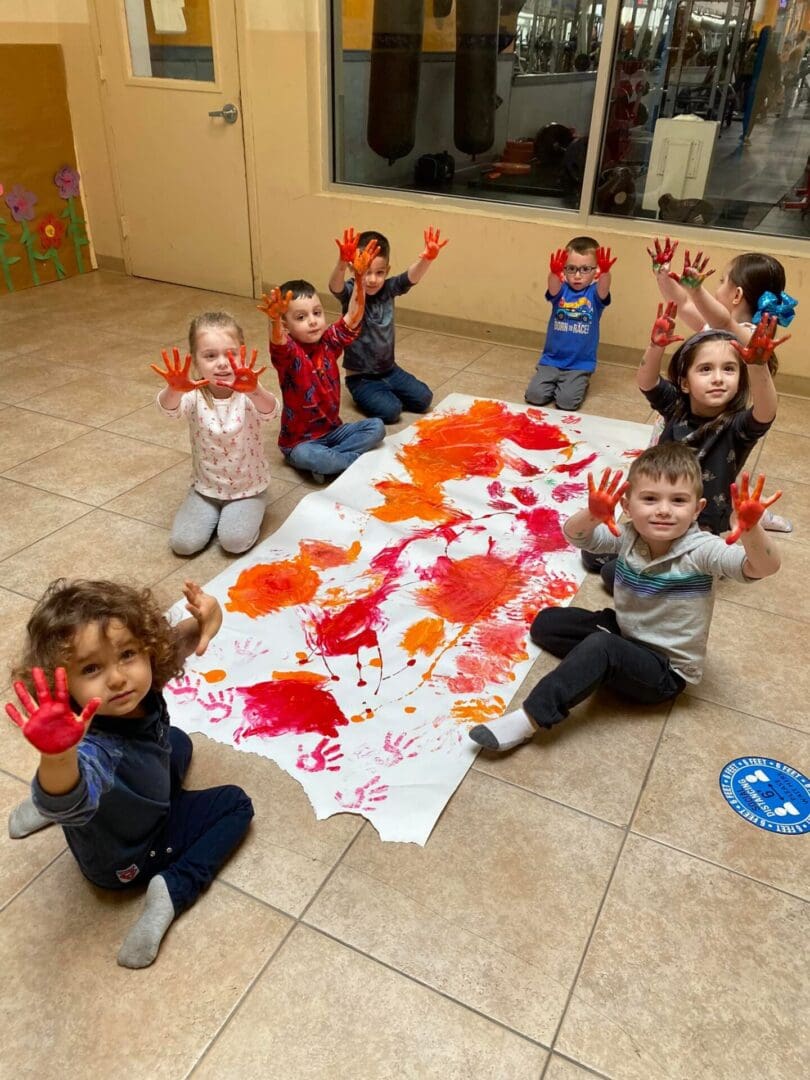 A group of kids painting using red colored paint