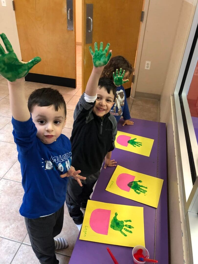 A group of kids painting using green colored paint