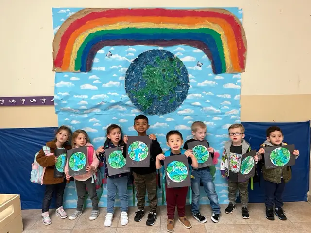 Children standing together holding drawings of earth